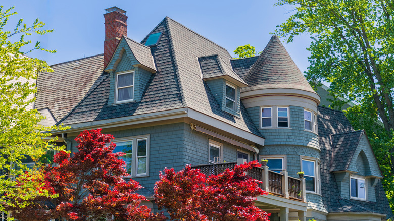 Bright red foliage in front of blue Queen Anne-style house.