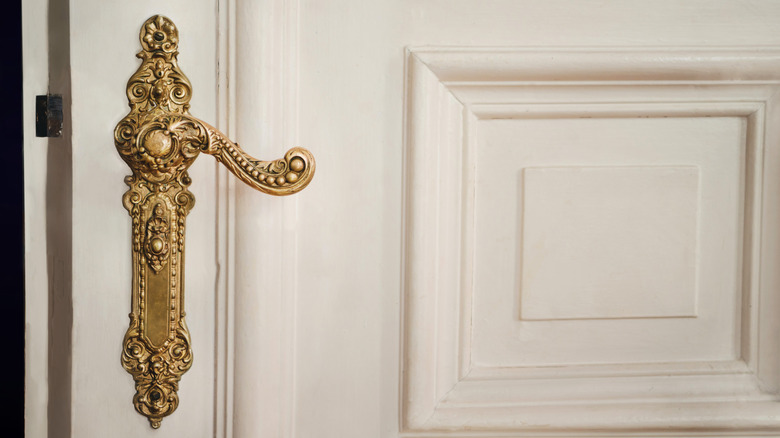 Old white door with antique brass door handle.