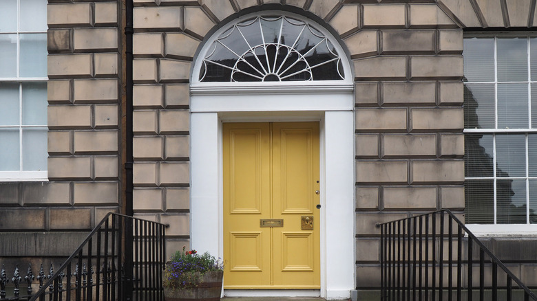 Large transom window over bright yellow front door.