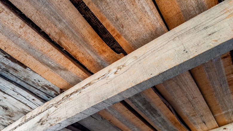 Old wooden ceiling held up by thick wooden beam.