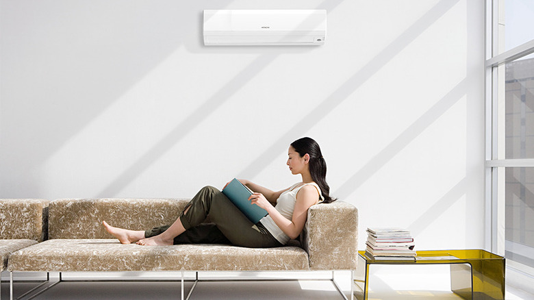 Hitachi air conditioner mounted on the wall above a woman reading on a couch