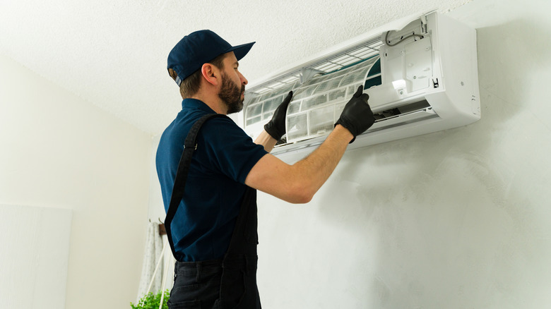 Male technician fitting air conditioning unit inside home