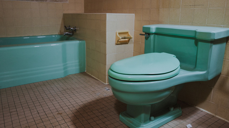 Teal-colored toilet and bathtub in an old bathroom