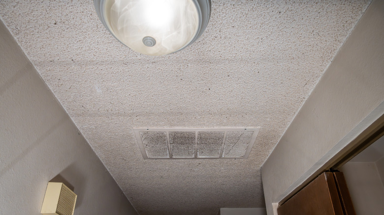 White popcorn ceiling with a light and vent in the middle
