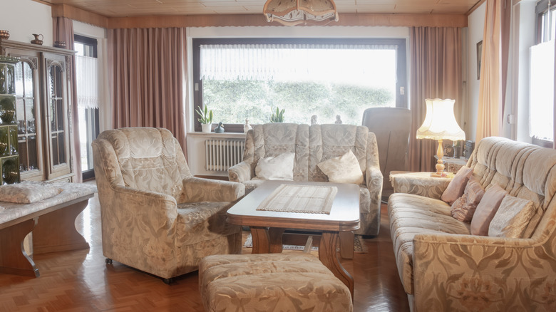 A floral sofa set in front of puffy curtains in a living room