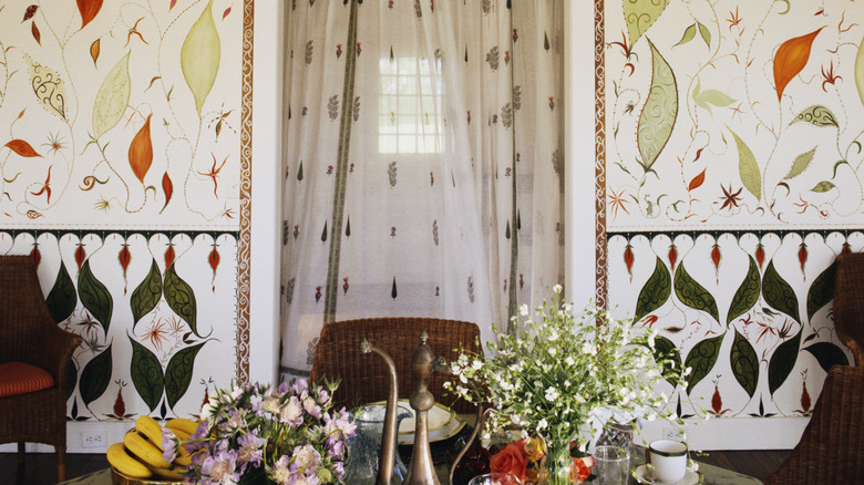 A busy wallpaper in a dining room with large shapes drawn on it and a border