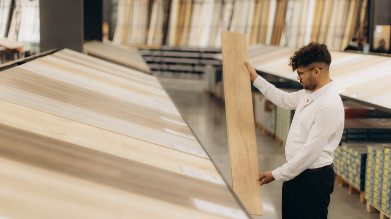 Man holding and looking at a wood plank in a store