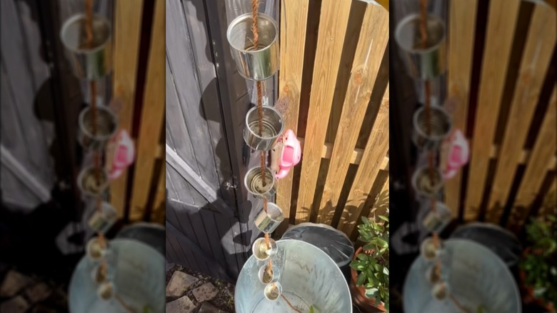 Rain chain made out of rope and tin cans emptying into a metal bucket