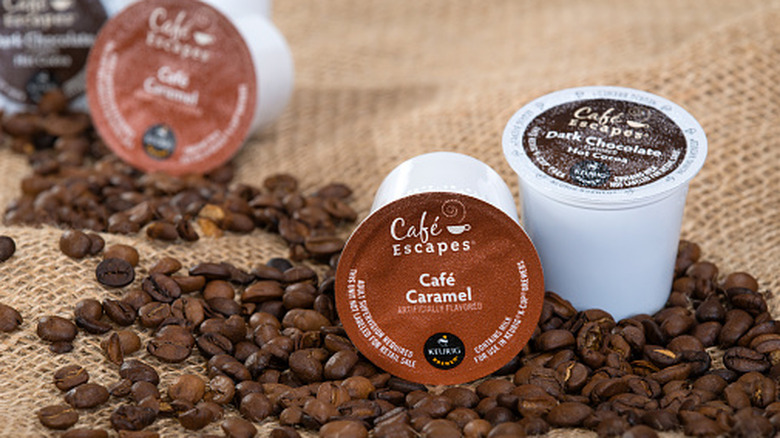 Multiple coffee pods sit on whole coffee beans