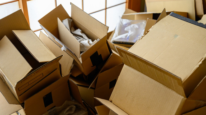 A pile of open cardboard boxes, some with plastic and paper filling