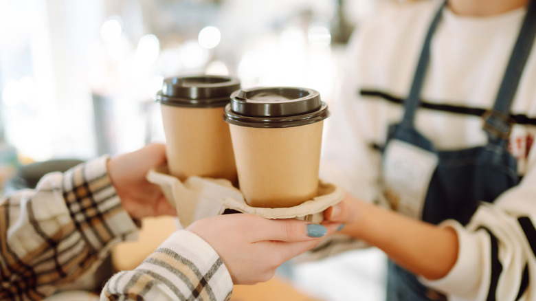 Barista giving person coffee in two disposable paper coffee cups