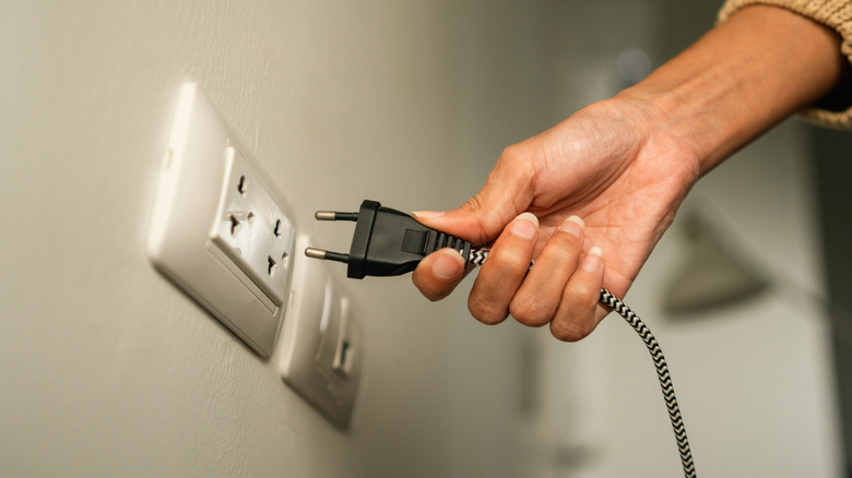 hand removing plug from outlet