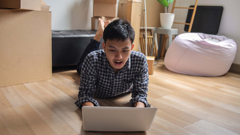 Man with no furniture using a laptop on the floor.