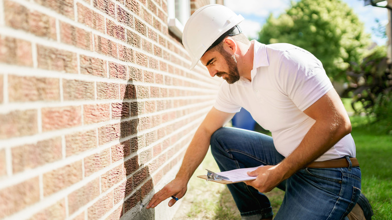 Man with clipboard inspecting exterior brick