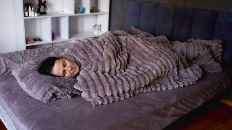Woman lying under a purple weighted blanket