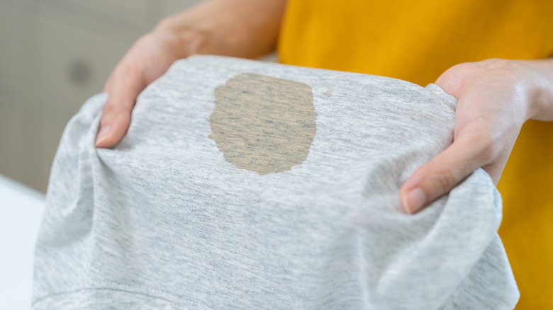 Person holding oil stained gray colored garment