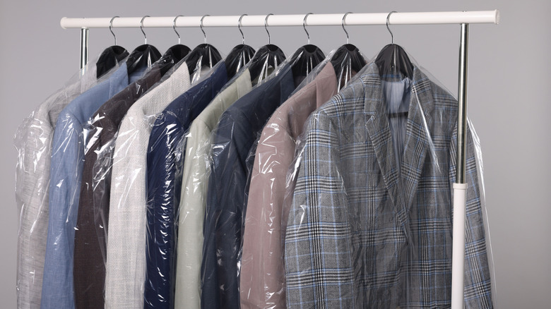 Multiple suits on rack in dry cleaning bags