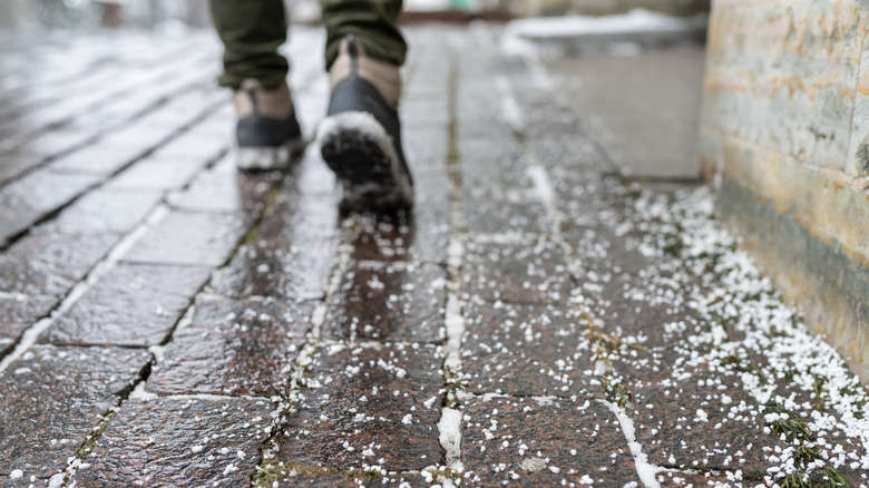 Boots walking on salt-covered sidewalk in winter