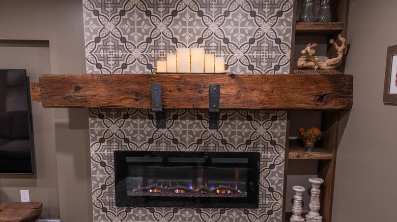 A reclaimed wood mantel above an electric fireplace paired with bold patterned tiling