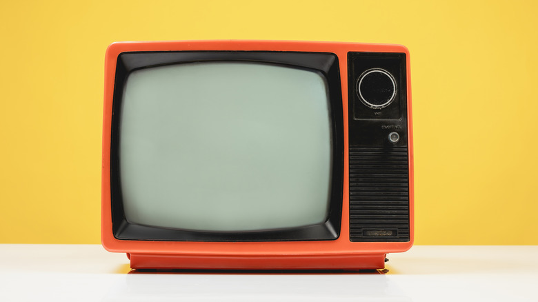 A retro orange TV against a bold yellow background
