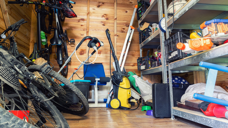 a disorganized shed full of tools and bikes, with tools stacked on metal shelving