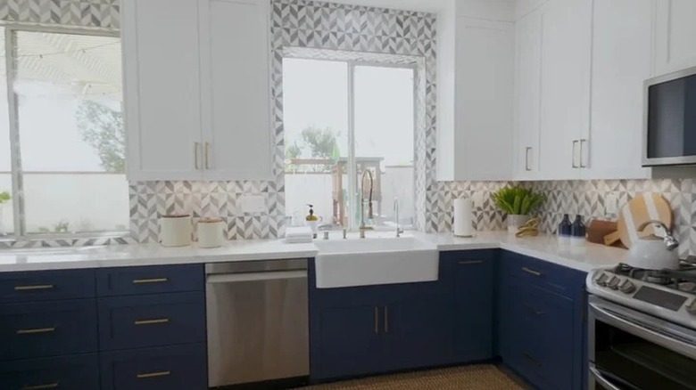Backsplash of gray and white tiles stretches up to ceiling on window wall.