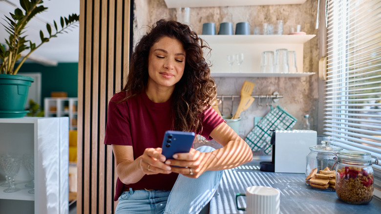 Woman on phone in kitchen with blinds