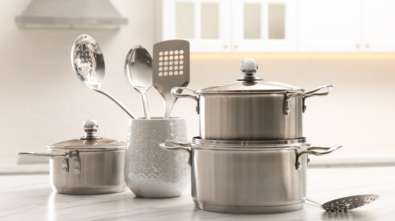 clean pots, lids, and cookware on a countertop ready to be put away