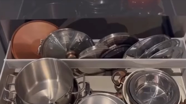 Drawer divider holding back a row of pot lids