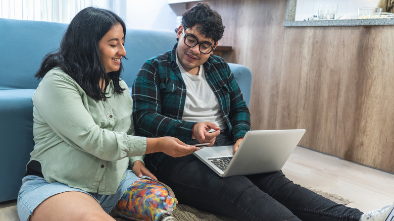 Two people shopping online for furniture and looking at a credit card