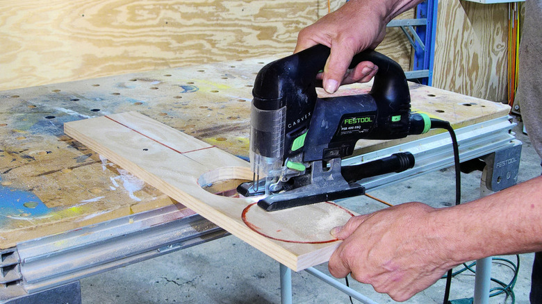 cutting a wooden disc with a handheld jigsaw.