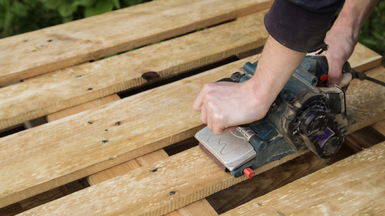 A person sanding a wood pallet