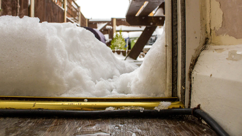 Bottom of door in winter with snow leaking in