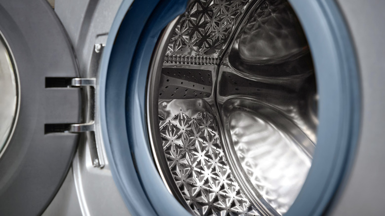 A woman pinches her nose at the bad smell of laundry recently removed from the washing machine behind her.