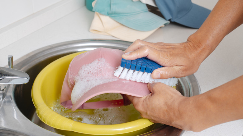Person handwashing a pink baseball cap