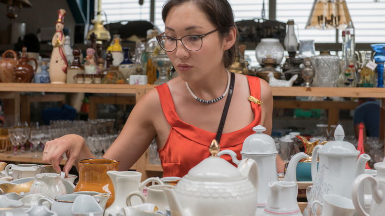 A woman in a thrift store shopping for glassware
