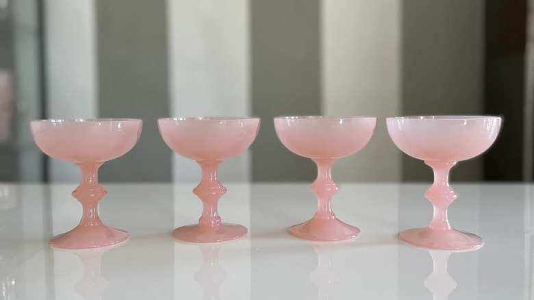 Four pink opaline glasses in a row on a table
