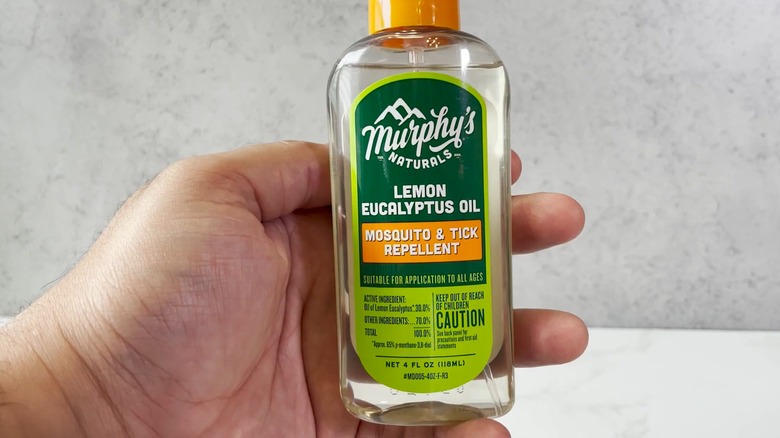 A hand holding a bottle of Murphy's Naturals Mosquito and Tick Repellent