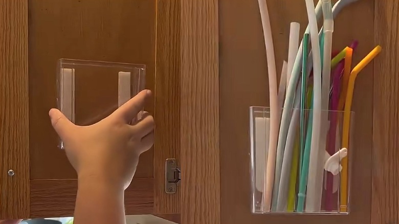 Dollar Tree plastic organizer hanging with disposable straws inside wood cabinet door