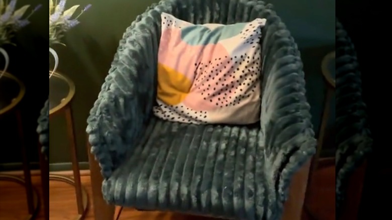 Closeup of chair upholstered with green fabric and a pillow