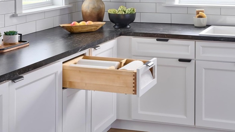open paper towel drawer with a roll on a rod, as well as two stored behind it
