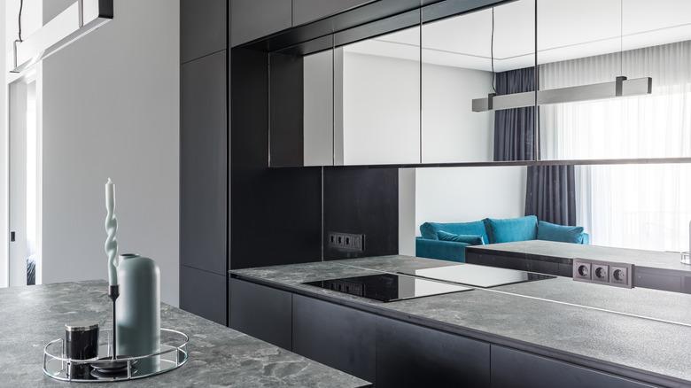 Mirrored backsplash in kitchen with dark cabinetry