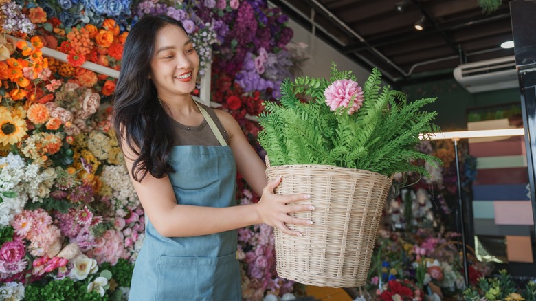 Young woman smiling with DIY woven basket filled with artificial flowers and greenery
