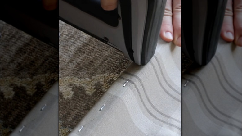 Using a staple gun to secure plaid fabric to the underside of an IKEA bench seat