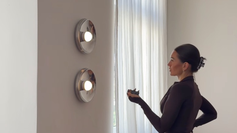 Woman using remote to control DIY lighting made using IKEA AFTONHAJ metal serving bowl