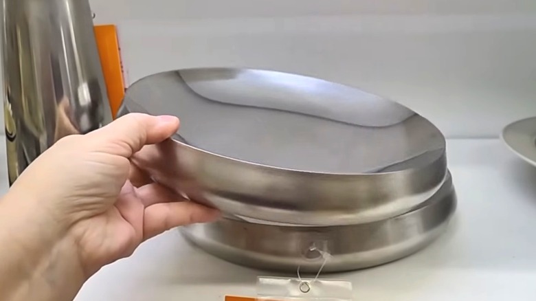 Person grabbing IKEA AFTONHAJ metal serving bowl from a shelf