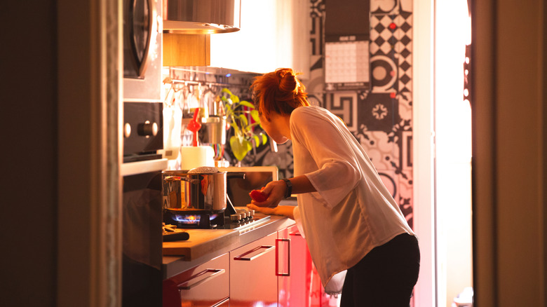 Woman cooking in a small kitchen with limited counter space