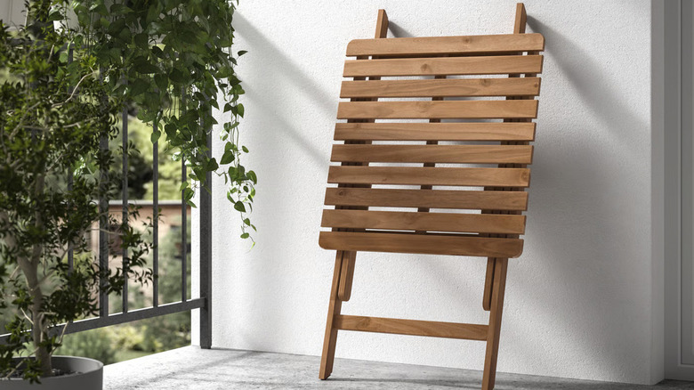 A folded IKEA ASKHOLMEN outdoor table up on a balcony