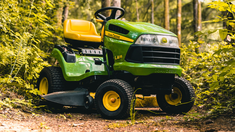 A John Deere LA 115 parked in the woods