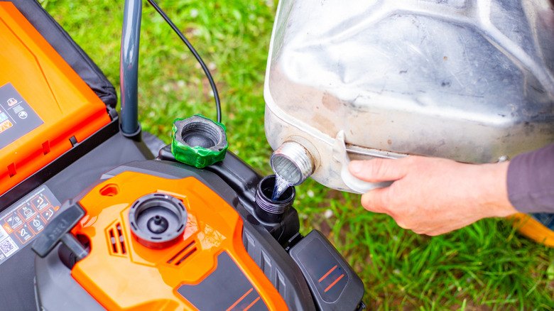 a gardener fills a lawn mower with gas